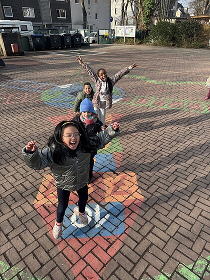Kinder springen auf dem Schulhof. Bewegung und Freude gehören fest zu unseren Schulalltag- Lernen mit Spaß und Energie.