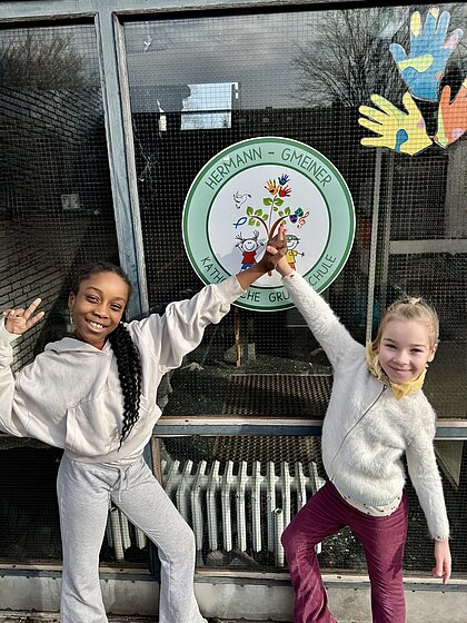 Zwei Kinder vor dem Schullogo Mit Freude, Bewegung und Teamgeist starten unsere Schüler in den Tag.
