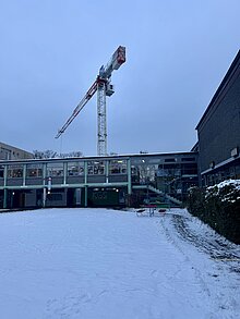 Blick auf unsere Schule an einem Wintermorgen. Dahinter sieht man den Kran, der gerade unseren Neubau errichtet.